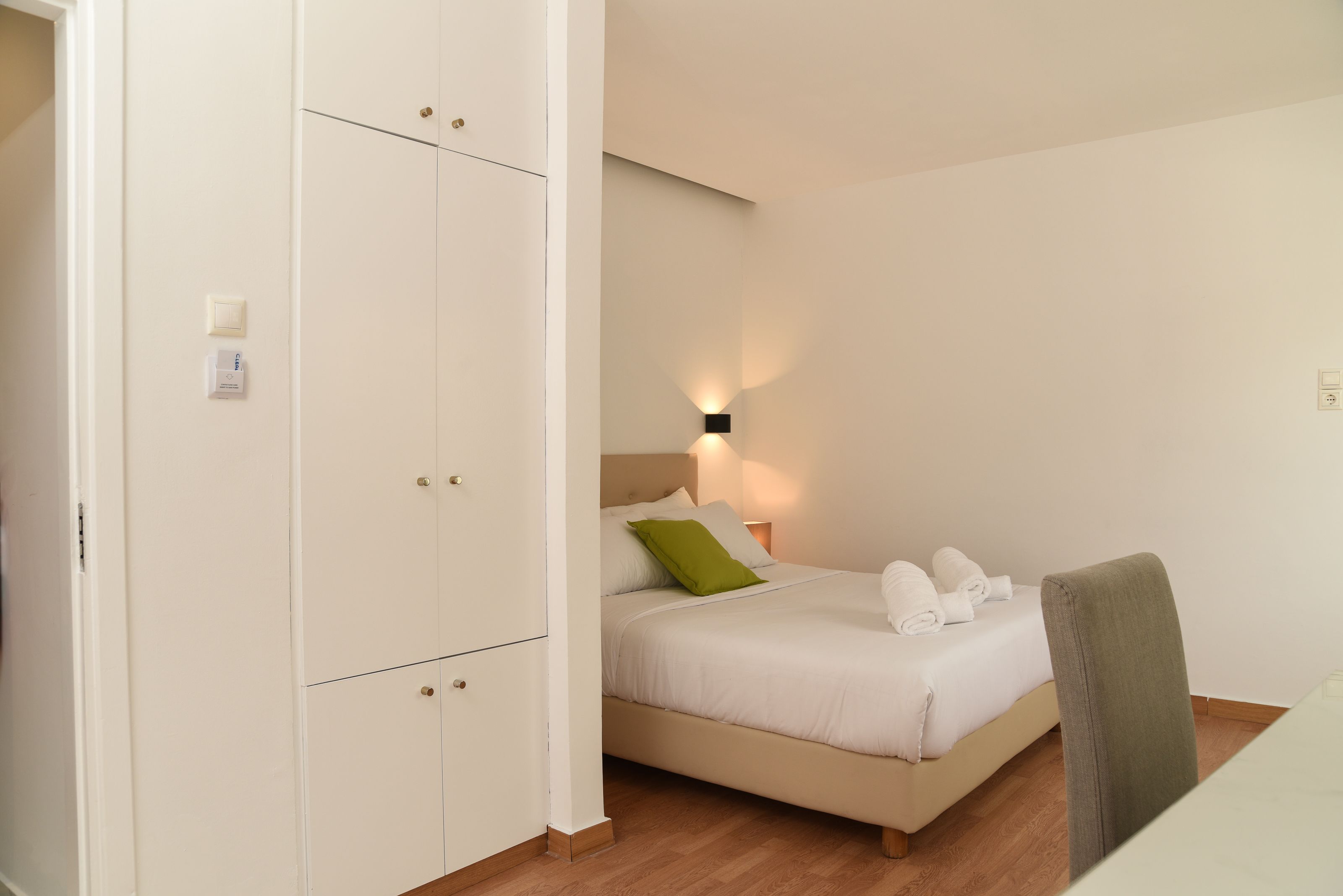 A bedroom with a bed, a nightstand, a wall-mounted light, and a wardrobe.