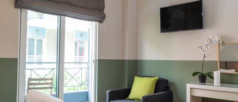 Habitación de hotel con dos camas, televisión, una silla y ventana con vista.