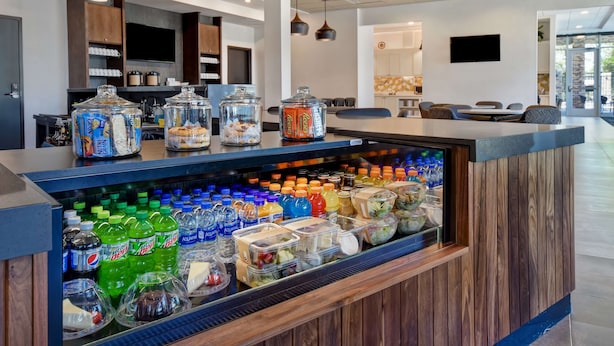 Een moderne hotellobby met een automaat voor drankjes, een zithoek en een televisie aan de wand.