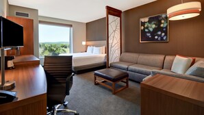 Een hotelkamer met een bed, een bank, een bureau, een stoel en een televisie.