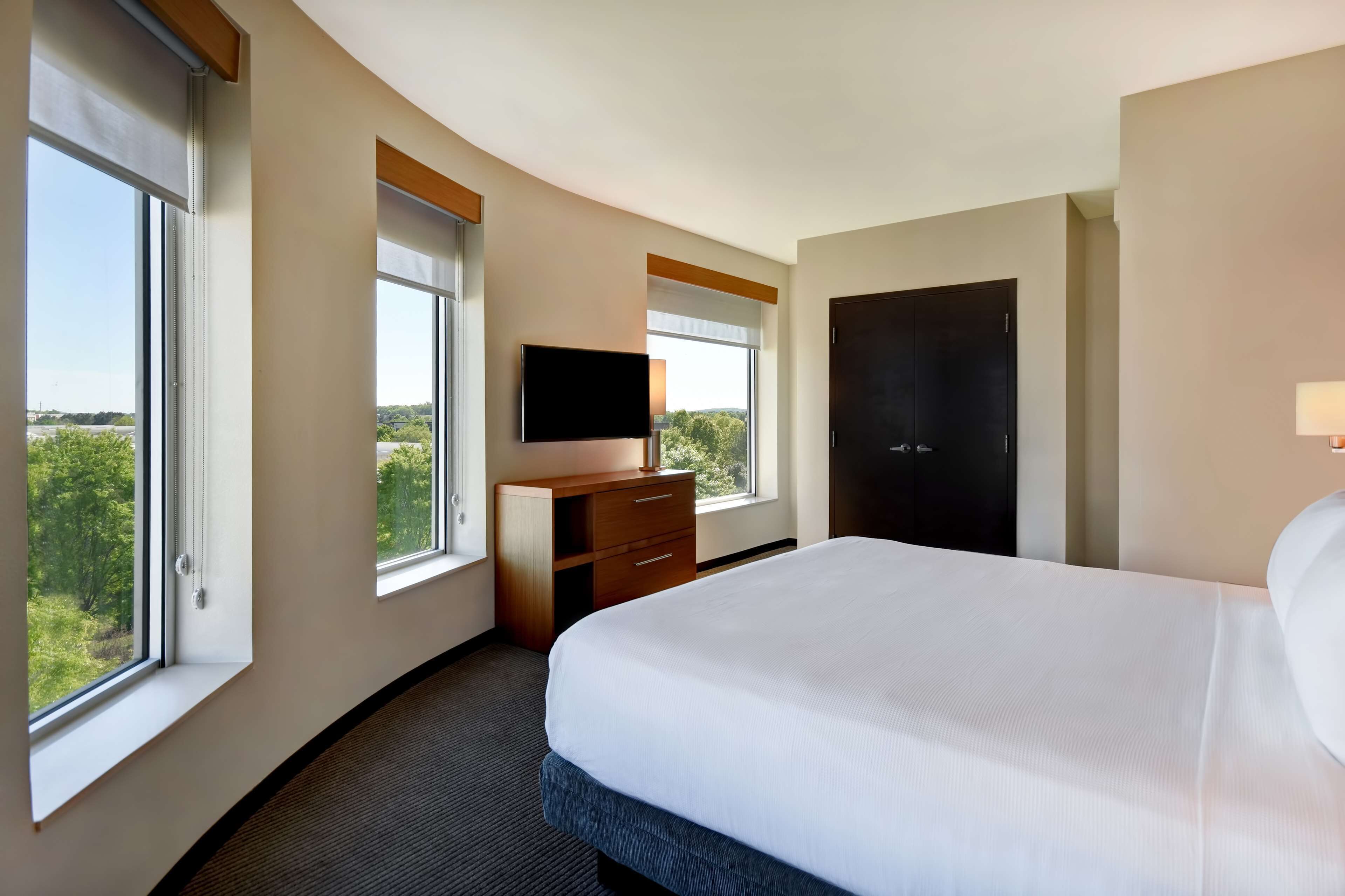 Une chambre d’hôtel avec un grand lit, un téléviseur à écran plat, une armoire et un bureau.