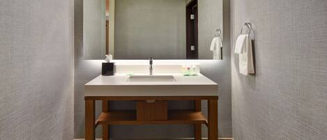 A modern bathroom with a wooden vanity, a large mirror, and a wall-mounted towel rack.