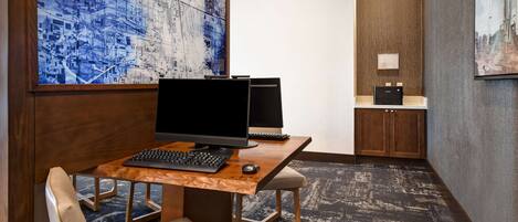 A modern office space with a wooden desk, two monitors, a keyboard, and a chair.