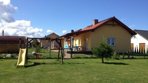 Et boligområde med et gult hus, gyngestativ og rutschebane i haven.