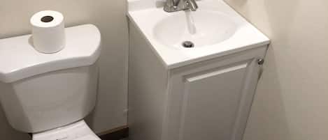 A bathroom with a toilet, a sink, and a hand dryer.