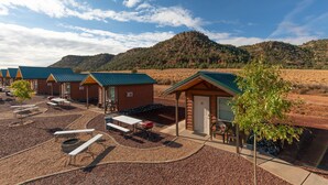 A campground with multiple cabins, picnic tables, and a clear view of a mountain in the background.