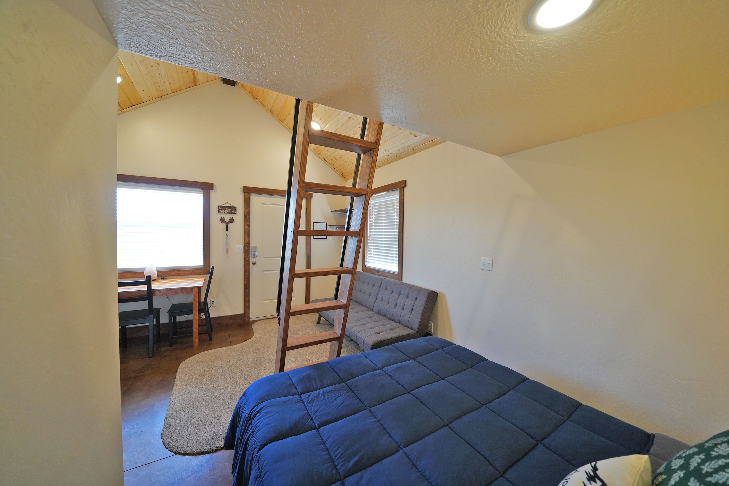 A bedroom with a loft bed, a desk, and a chair.