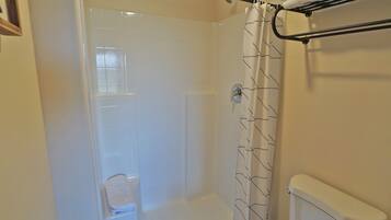 A bathroom with a shower, toilet, and a towel rack.