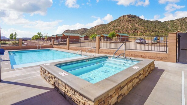 A pool area with two pools, a stone wall, and a view of a mountainous landscape.