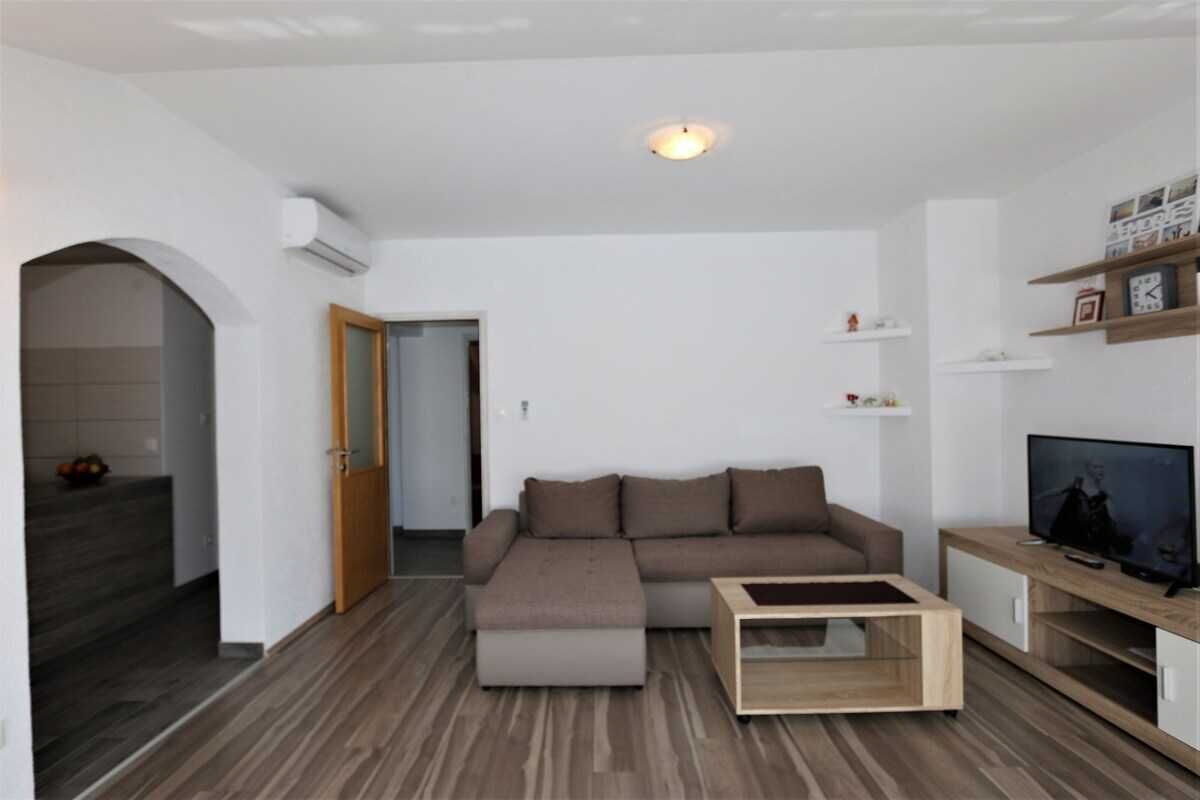 A modern living room with a sectional sofa, a coffee table, a TV, and built-in shelving.