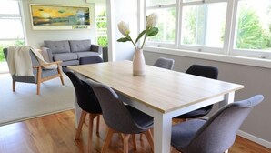 Un comedor con una mesa de madera, sillas tapizadas en gris y un jarrón con flores.
