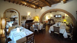 Un restaurante con varias mesas, vigas de madera en el techo y arcos de ladrillo.