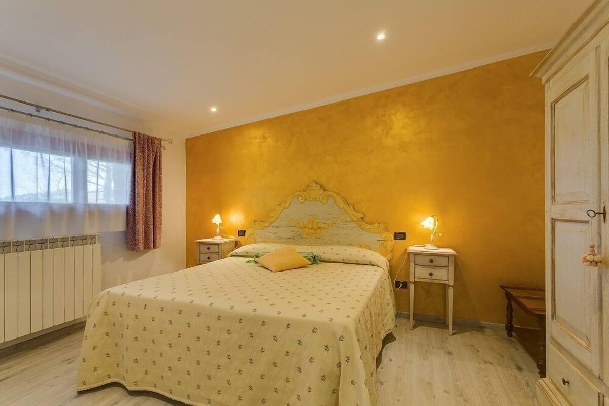 Un dormitorio con una cama, dos mesitas de noche, un radiador y un armario.