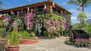 A building with a balcony, potted plants, and flags. - ZonaZ Boutique Hotel (Puerto Vallarta)