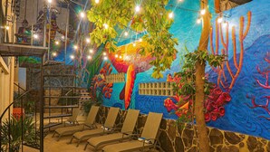 A lounge area with a mural, lounge chairs, and a staircase. - ZonaZ Boutique Hotel (Puerto Vallarta)