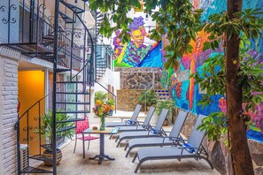 A courtyard with a mural, outdoor seating, and a staircase. - ZonaZ Boutique Hotel (Puerto Vallarta)