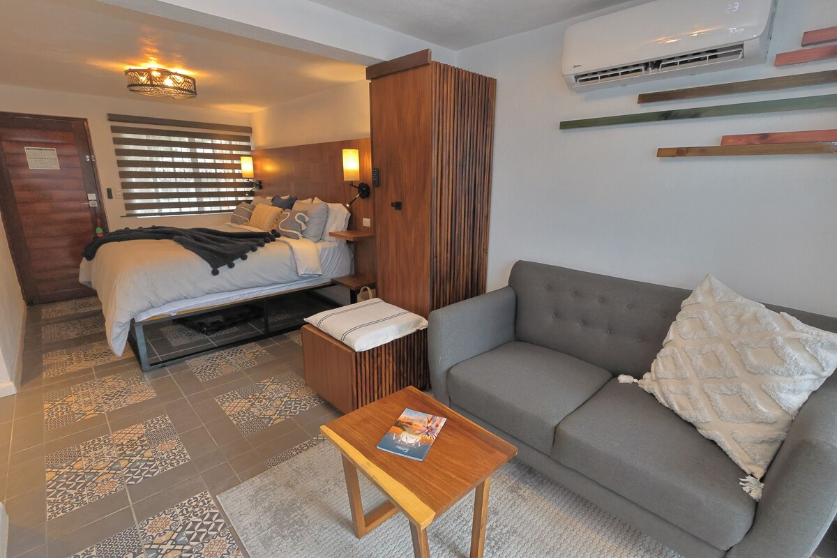 Ein Hotelzimmer mit einem Bett, einer Couch, einem kleinen Tisch und einer Wand-Klimaanlage.