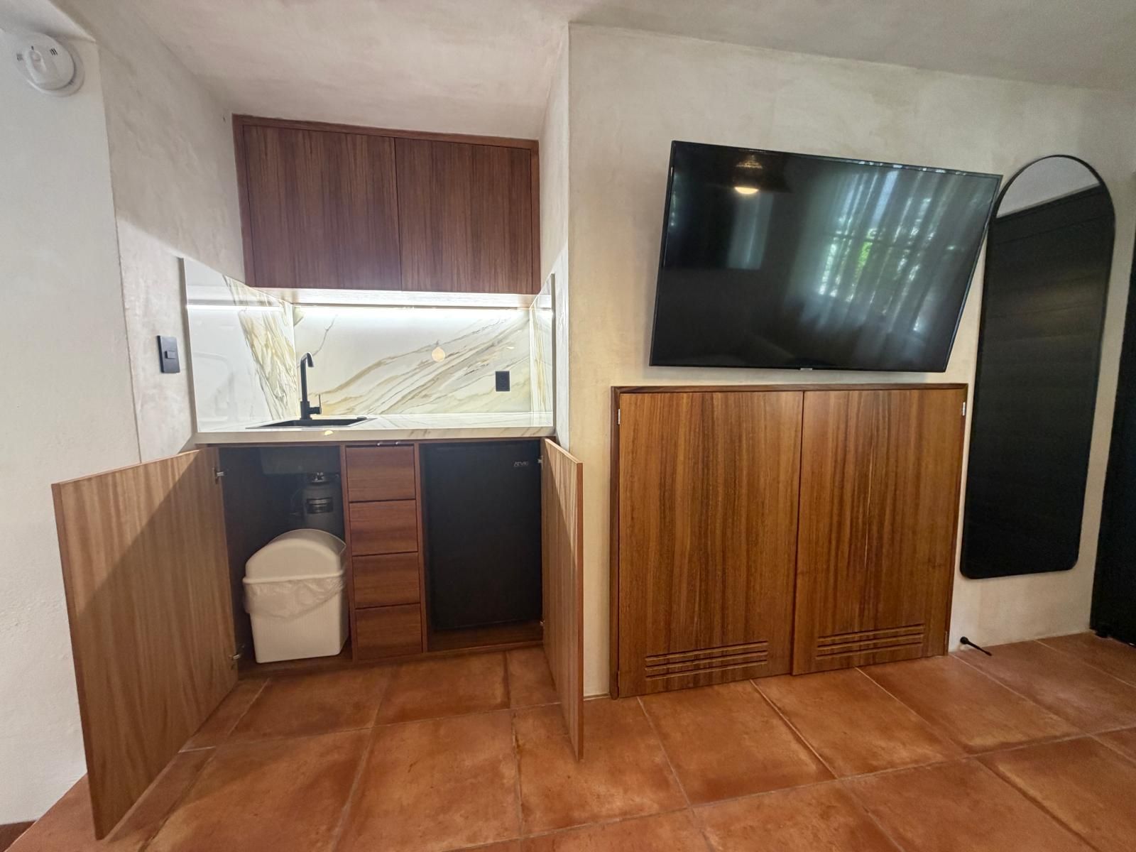 A compact kitchen with a built-in TV, a sink, and cabinets.