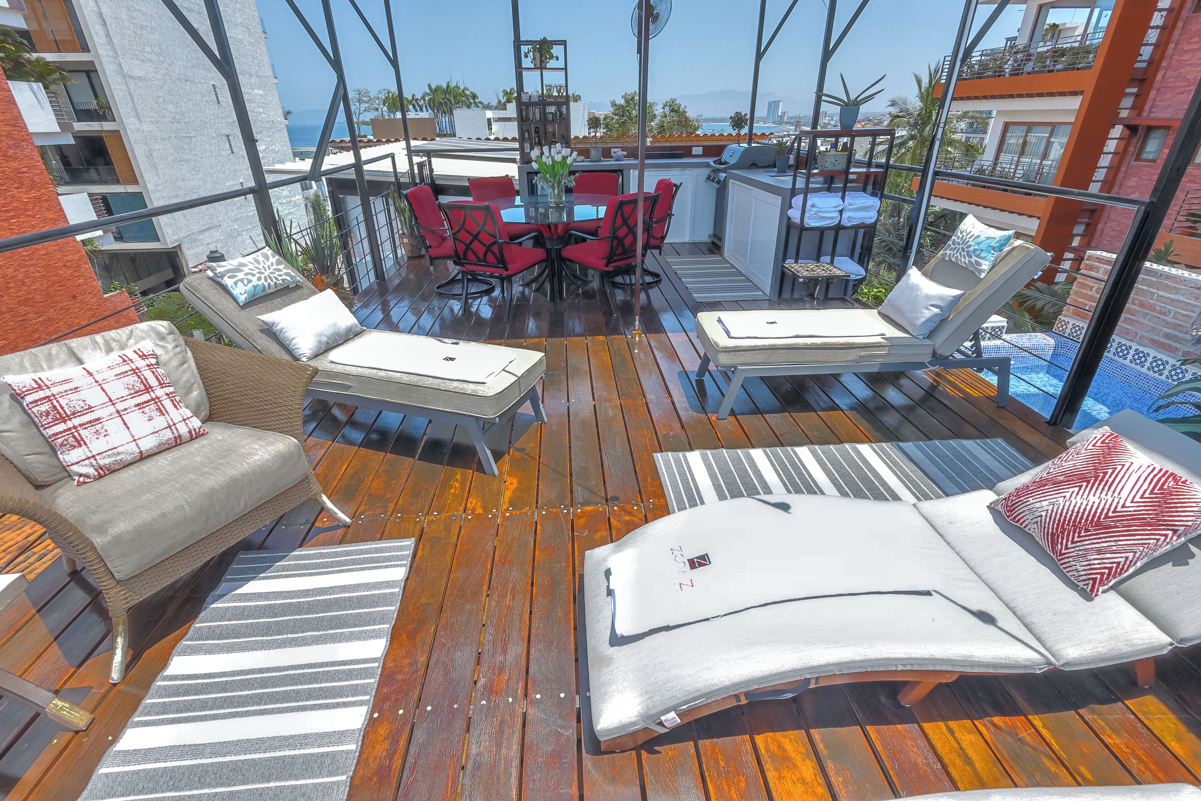 Una terraza en la azotea con mobiliario exterior, una mesa y vistas a la ciudad.