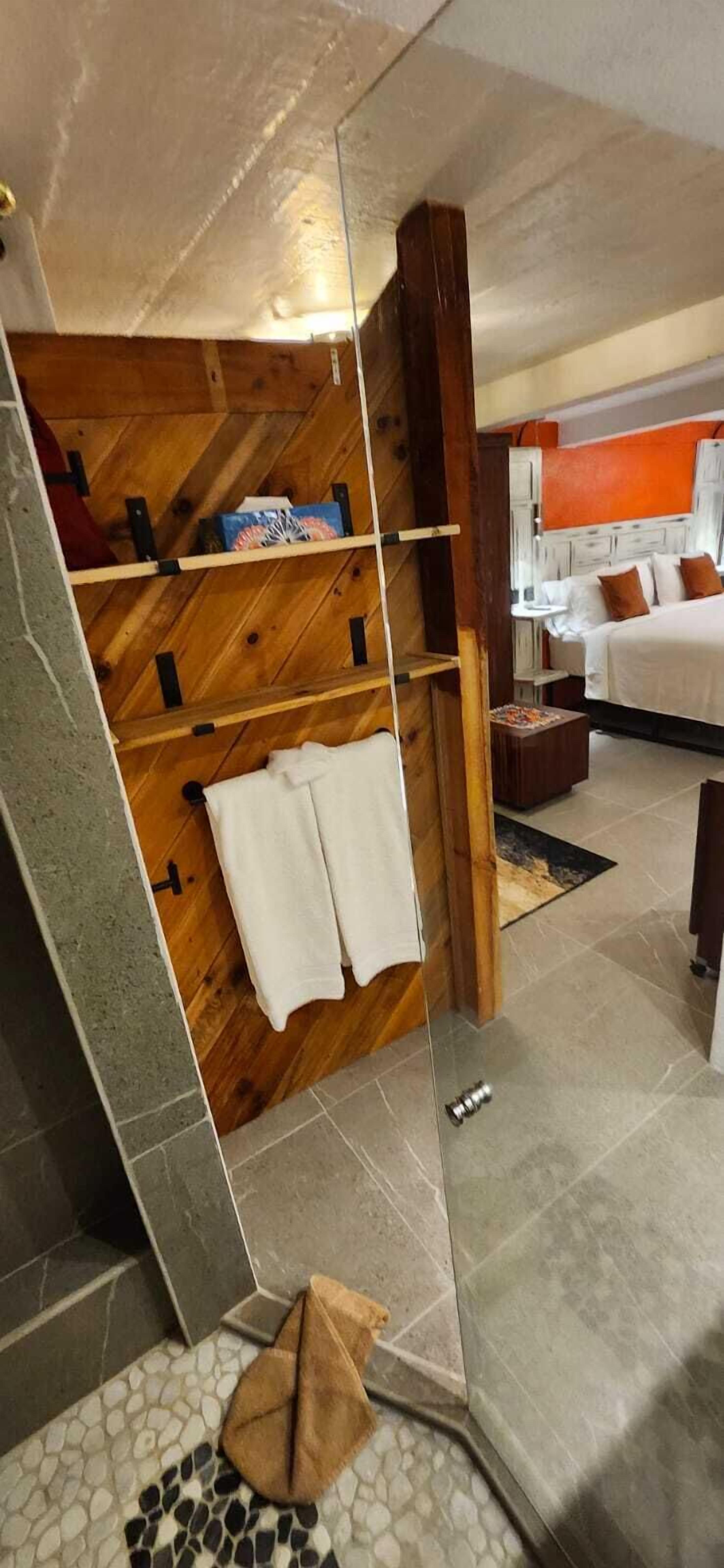 Une salle de bain moderne avec un meuble-lavabo en bois, une cabine de douche en verre et un sol carrelé.