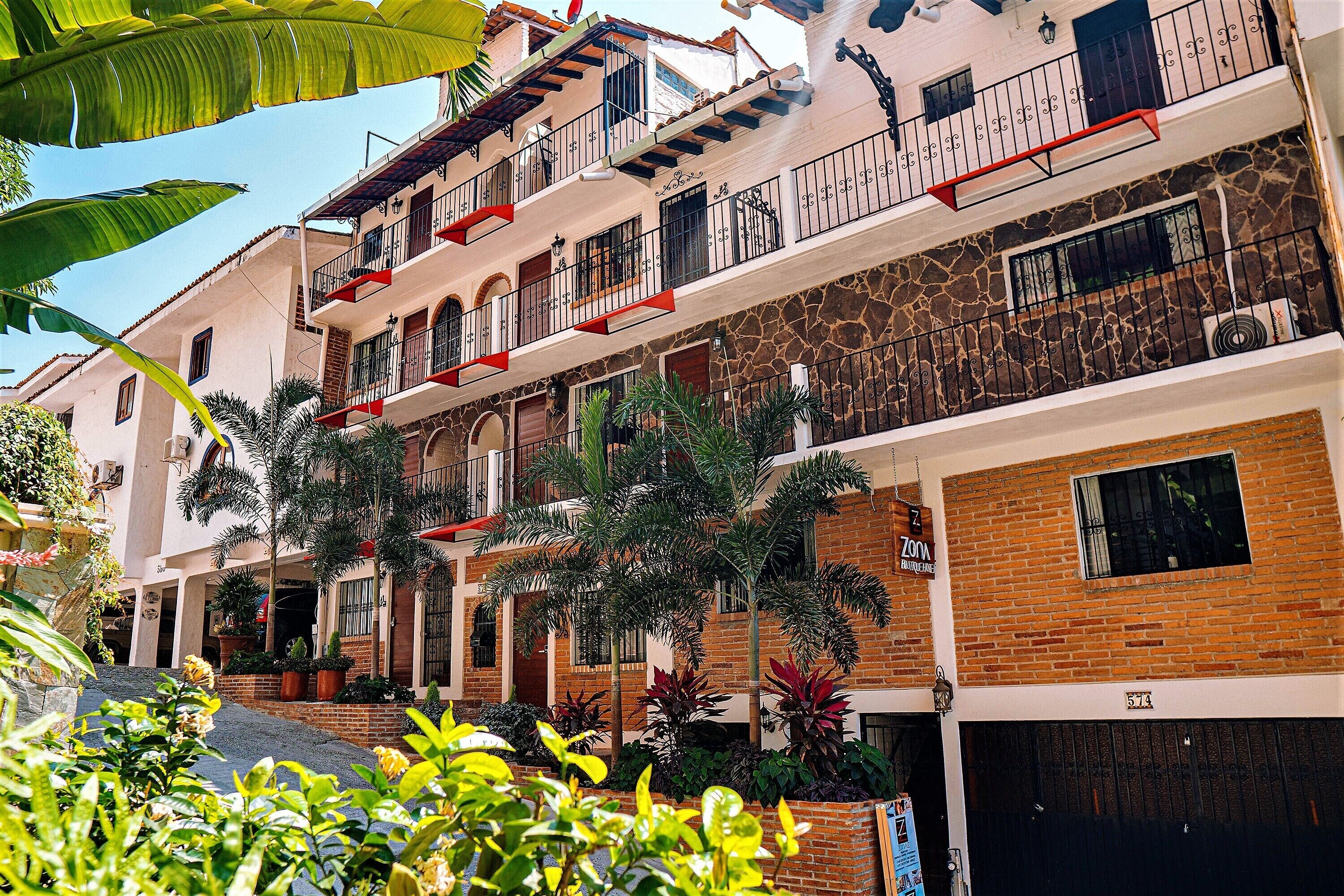 A multi-story building with balconies, a brick facade, and a gated entrance.