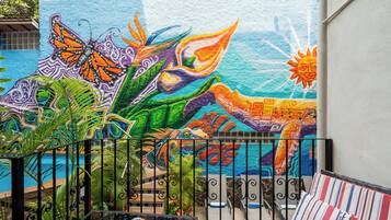 A colorful mural with a butterfly, plant, and sun on a wall.