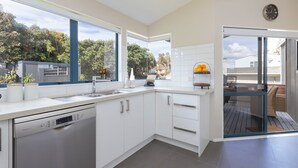 Una cocina moderna con armarios blancos, un lavavajillas Bosch y ventana con vistas a un jardín.