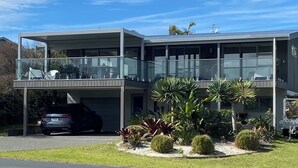 Una casa moderna de dos pisos con balcón, garaje y un jardín bien cuidado.
