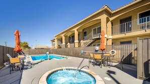 A pool area with a hot tub, lounge chairs, and umbrellas. - Quality Inn & Suites Victorville – Hesperia (Hesperia)