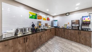 A modern kitchen with white tiles, wooden cabinets, and various appliances like a waffle maker and coffee machine. - Quality Inn & Suites Victorville – Hesperia (Hesperia)