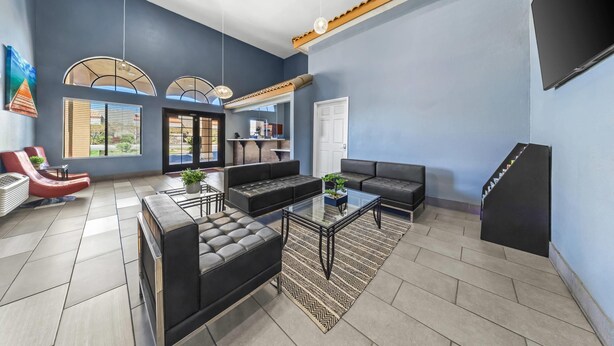 A modern living room with a sofa, armchairs, a coffee table, and a TV. - Quality Inn & Suites Victorville – Hesperia (Hesperia)