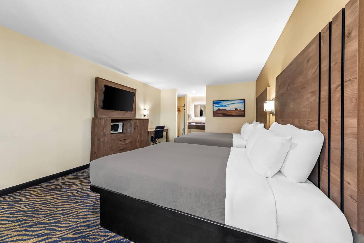 A hotel room with a large bed, a TV, a desk, and a painting on the wall.