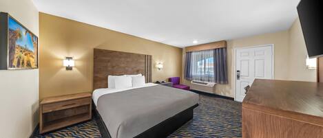 A hotel room with a bed, nightstand, desk, and a television.