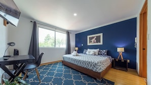 A bedroom with a bed, a desk, a chair, a TV, and a window. - Casa Hidalgo (Mexico City)