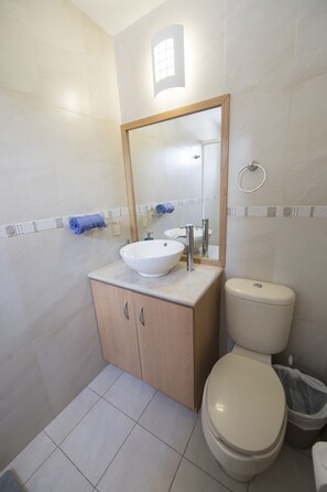 Ein Badezimmer mit einem weißen Waschbecken, einem Holzschrank und einer Toilette.
