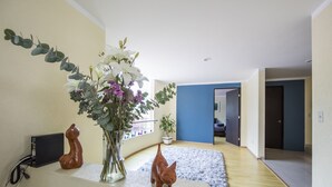 A living room with a wooden cat sculpture, a vase with flowers, and a small speaker on a table. - Casa Hidalgo (Mexico City)