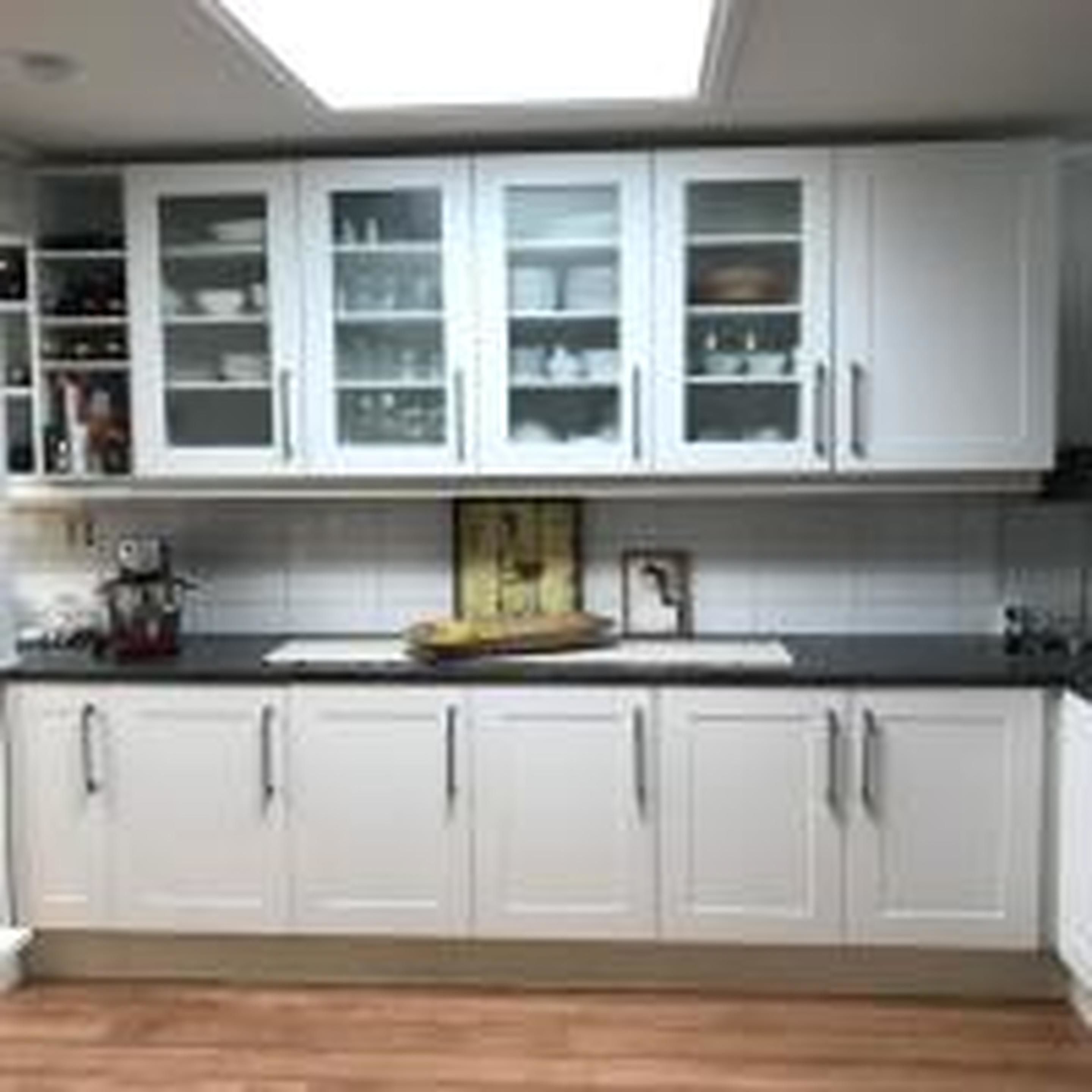 A modern kitchen with white cabinets, a central island, and a window above the sink.