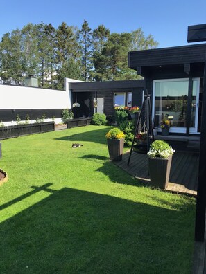 A modern house with a well-maintained lawn, outdoor seating area, and large windows. - Solferie Harald Hårfagresvei 27F (Kristiansand)