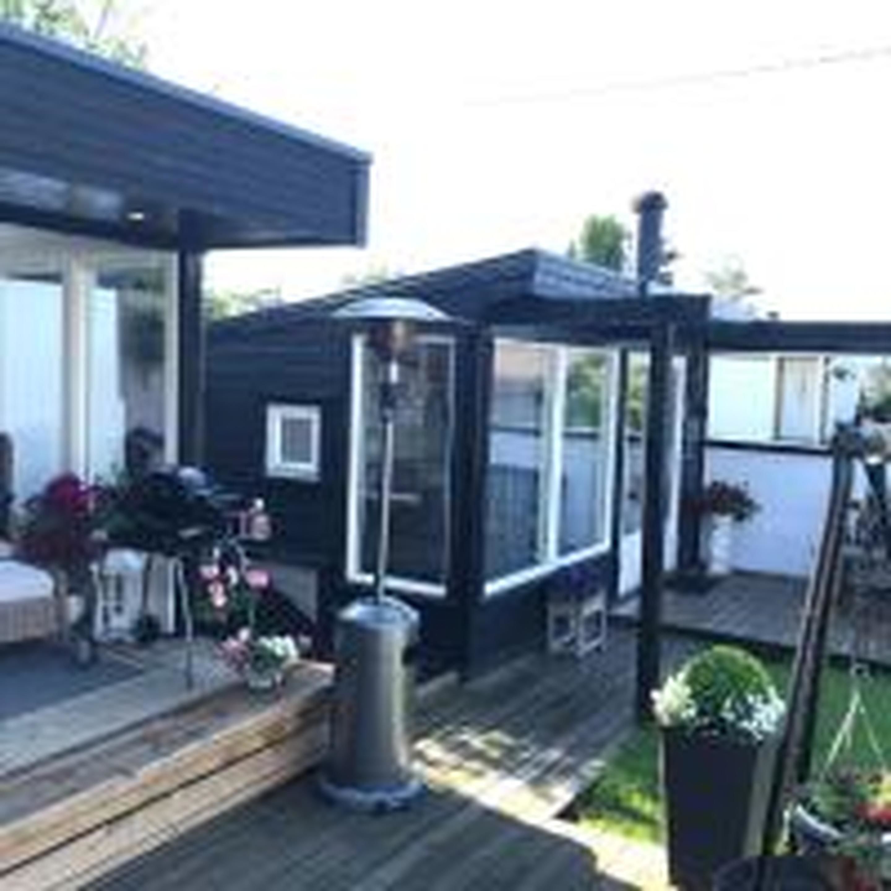 A modern house with a covered porch, a small deck, and a garden area with potted plants.