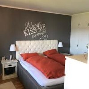 A bedroom with a bed, two nightstands, a wall decoration, and a bedside table. - Solferie Harald Hårfagresvei 27F (Kristiansand)
