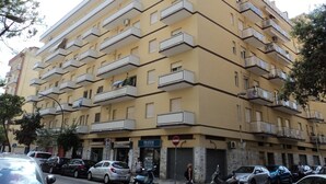 A multi-story yellow building with balconies, parked cars, and a 'PRATESI' sign indicating a business. - Nice Property throughout August (Pescara)