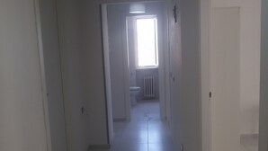 A narrow hallway with white walls and doors, leading to a bathroom with a toilet and radiator. - Nice Property throughout August (Pescara)