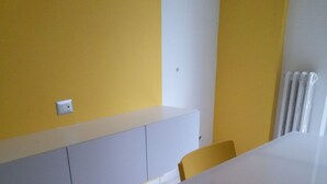 A room with a white table and yellow chairs, a white bench along the wall, and a radiator on the right. - Nice Property throughout August (Pescara)