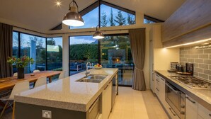 Una cucina moderna con una grande isola, elettrodomestici integrati e ampie finestre che offrono vista all'esterno.