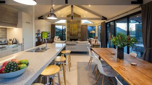 Una cucina moderna con isola centrale, sgabelli da bar e zona pranzo con tavolo e sedie in legno.