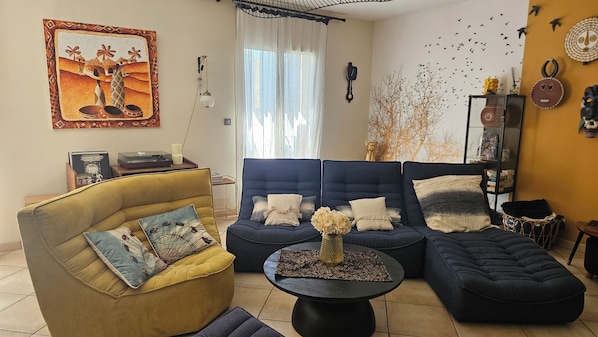 A living room with a sofa set, a yellow armchair, a coffee table, and a painting on the wall.