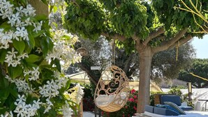 A garden with a hanging chair, a wooden bench, and a sofa with cushions. - Large country house with swimming pool, SPA, terrace, garden, WIFI access 5 min from Sanary  (Ollioules)