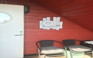 Une pièce avec un toit rouge, deux chaises en osier et une porte blanche.