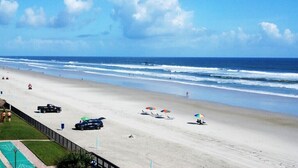 A beach with a clear sky, a few umbrellas, and a few people.