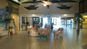 A spacious lobby with high ceilings, a large fan, and wicker furniture.